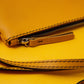 Bolso de cuero amarillo con costuras en hilo negro.